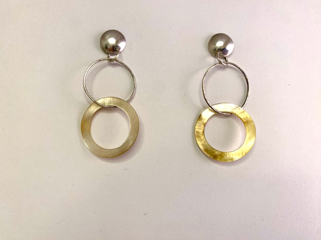 A pair of dangling earrings with silver-tone ball studs, double interlocking rings, and one larger textured gold-tone circular drop on each earring, shown on a plain off-white background.
