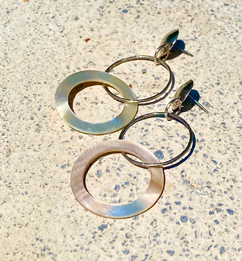 Sterling silver and mother of pearl double hoop earrings on gray background, close up view