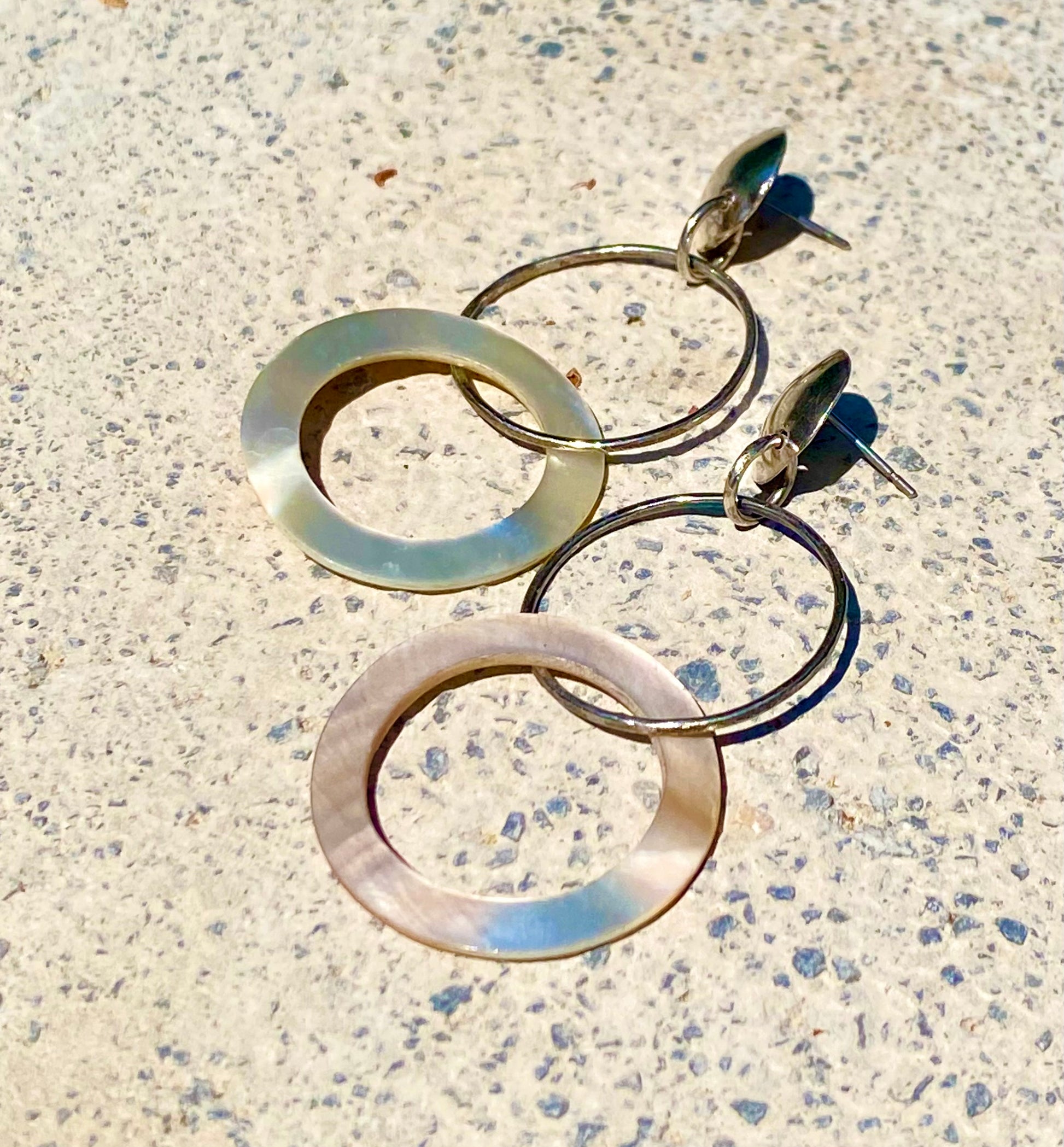 Sterling silver and mother of pearl double hoop earrings on gray background, close up view